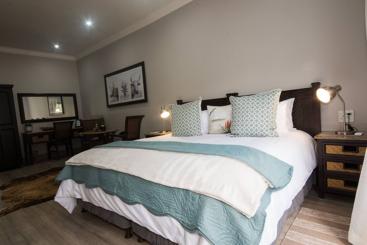 A neatly arranged bedroom with a large bed, a desk, and a chair.
