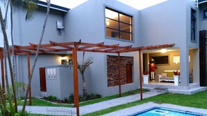 Ein modernes Haus mit Swimmingpool, überdachter Terrasse und einer Steinmauer.