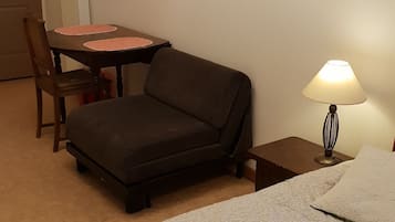 A room with a bed, a sofa, a table, and a chair.