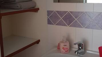 Une salle de bain avec un lavabo blanc, un miroir et un porte-serviettes.