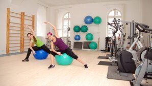 Een sportschool met trainingsapparatuur, waaronder fitnessballen en een Tunturi hometrainer.