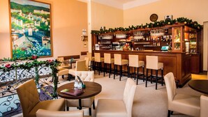 Een bar met verschillende zithoeken, een toog vol met flessen en een schilderij aan de muur.