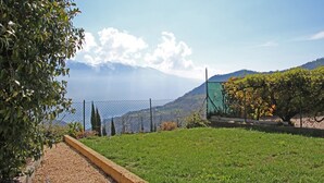 Uma área gramada com um caminho de cascalho, uma cerca de arame e vista para montanhas distantes.