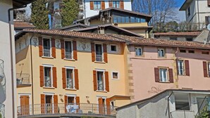 Um edifício residencial com vários andares, varandas, fachada de pedra e céu azul límpido.