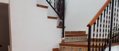 Una escalera con barandilla negra y un tapete rojo al pie.