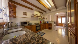 Una cocina con encimeras de granito, gabinetes de madera, microondas y estufa.