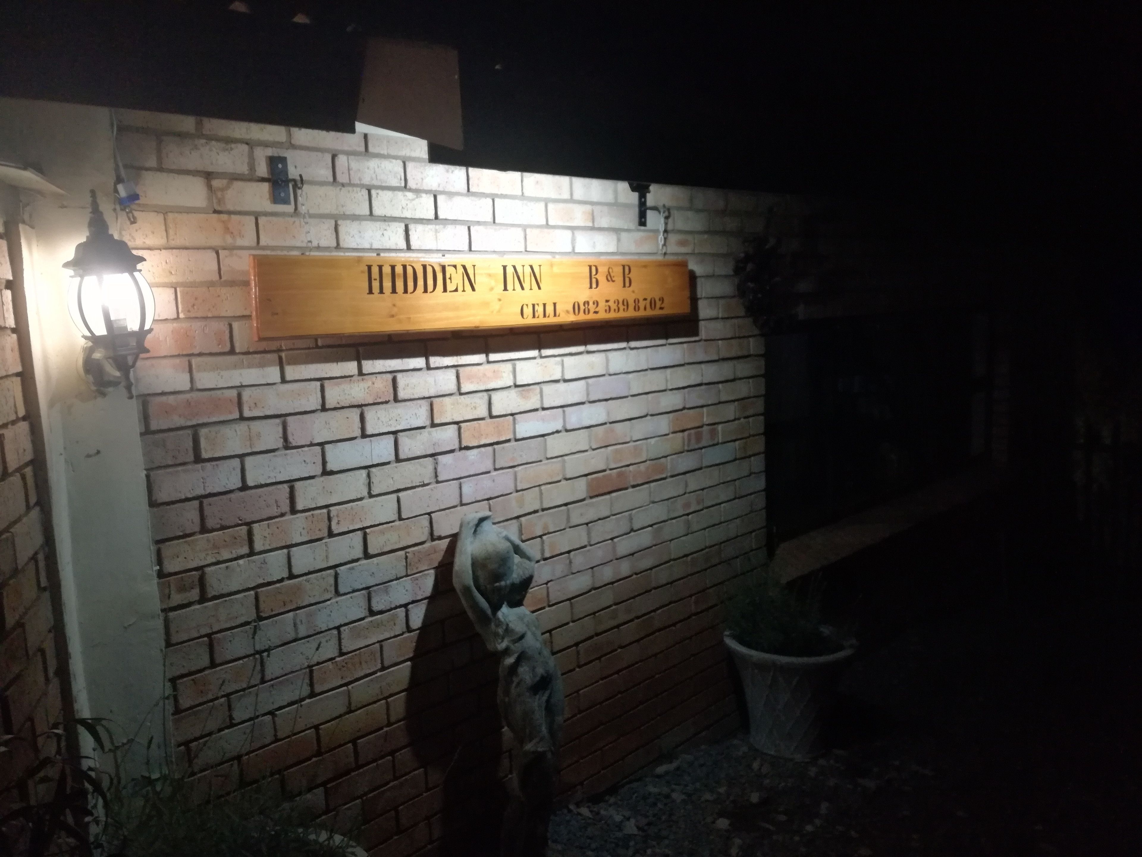 Un muro de ladrillo con un letrero que dice 'Hidden Inn B&B' y un número de teléfono.
