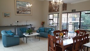 A spacious living area with two blue sofas, a wooden dining table, and a chandelier. - Hidden Inn (Pietermaritzburg)