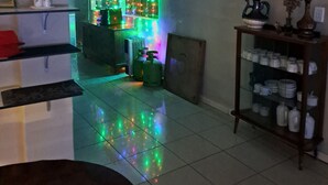 A room with a tiled floor, a shelf with decorative items, a wall with a colorful light display, and a cabinet with kitchenware. - Hidden Inn (Pietermaritzburg)