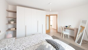 A bedroom with a bed, a desk, a chair, a wardrobe, and shelves with plants. - Casa del Borgo Vesio (Tremosine)