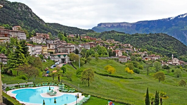 A hillside village with a swimming pool surrounded by lounge chairs and umbrellas. - Casa del Borgo Vesio (Tremosine)