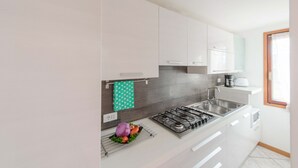 A modern kitchen with white cabinets, a gas stove, and a sink. - Casa del Borgo Vesio (Tremosine)