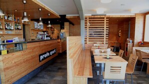 A modern restaurant with wooden accents, a bar area, and a long communal dining table. - Residence Prada (Trento)