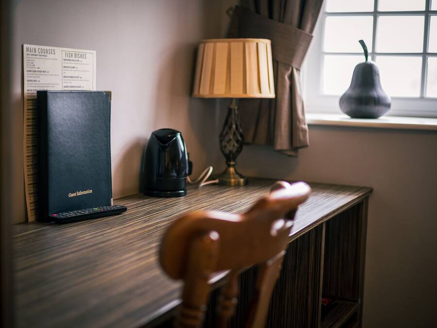 A wooden chair with a curved backrest, a black electronic device labeled 'Guest Information', a lamp, and a vase on a window sill.