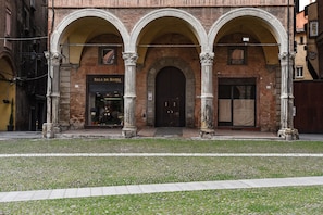 A building with three arched entrances, a visible shop named "Sala da Barra," and a cobblestone courtyard.