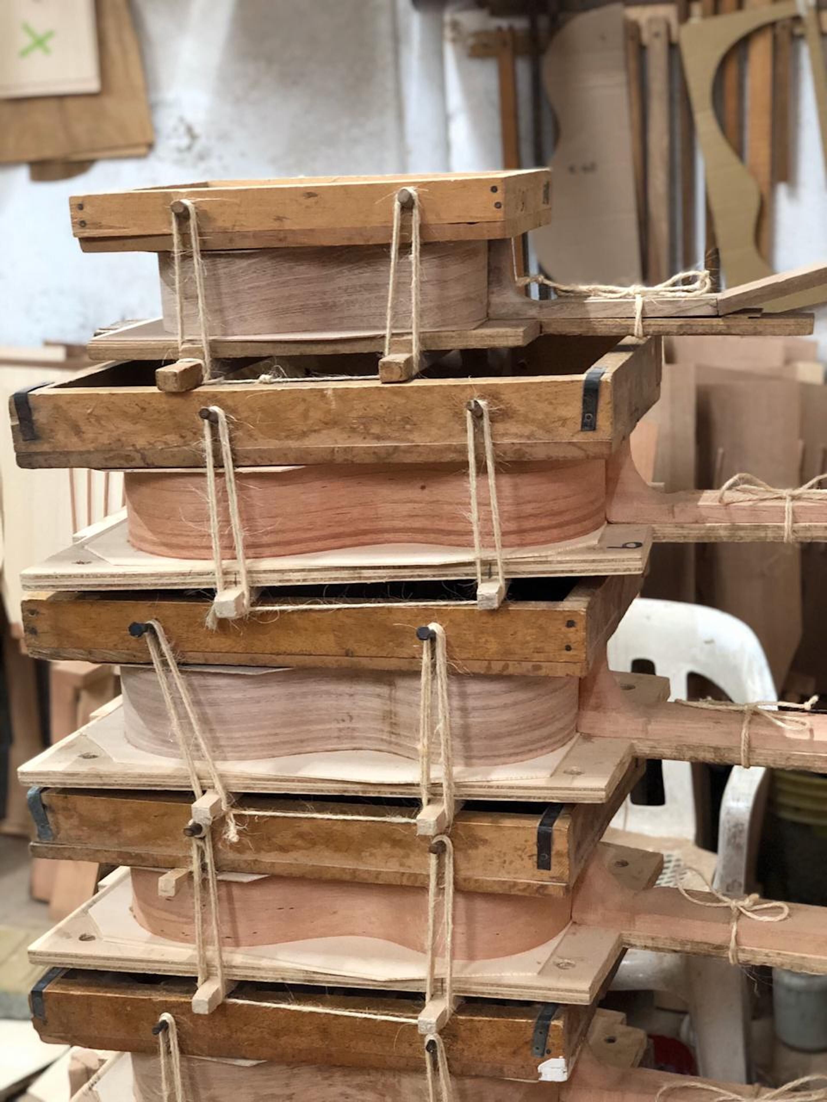 A stack of wooden boxes with ropes tied around them, likely used for storage or organization in a workshop or storage area.