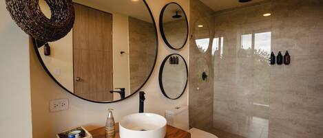 Un baño moderno con tocador de madera, un espejo grande y una ducha con mampara de vidrio.