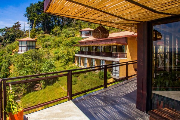 Una casa moderna con balcón, ventanas amplias y vistas a un jardín exuberante.