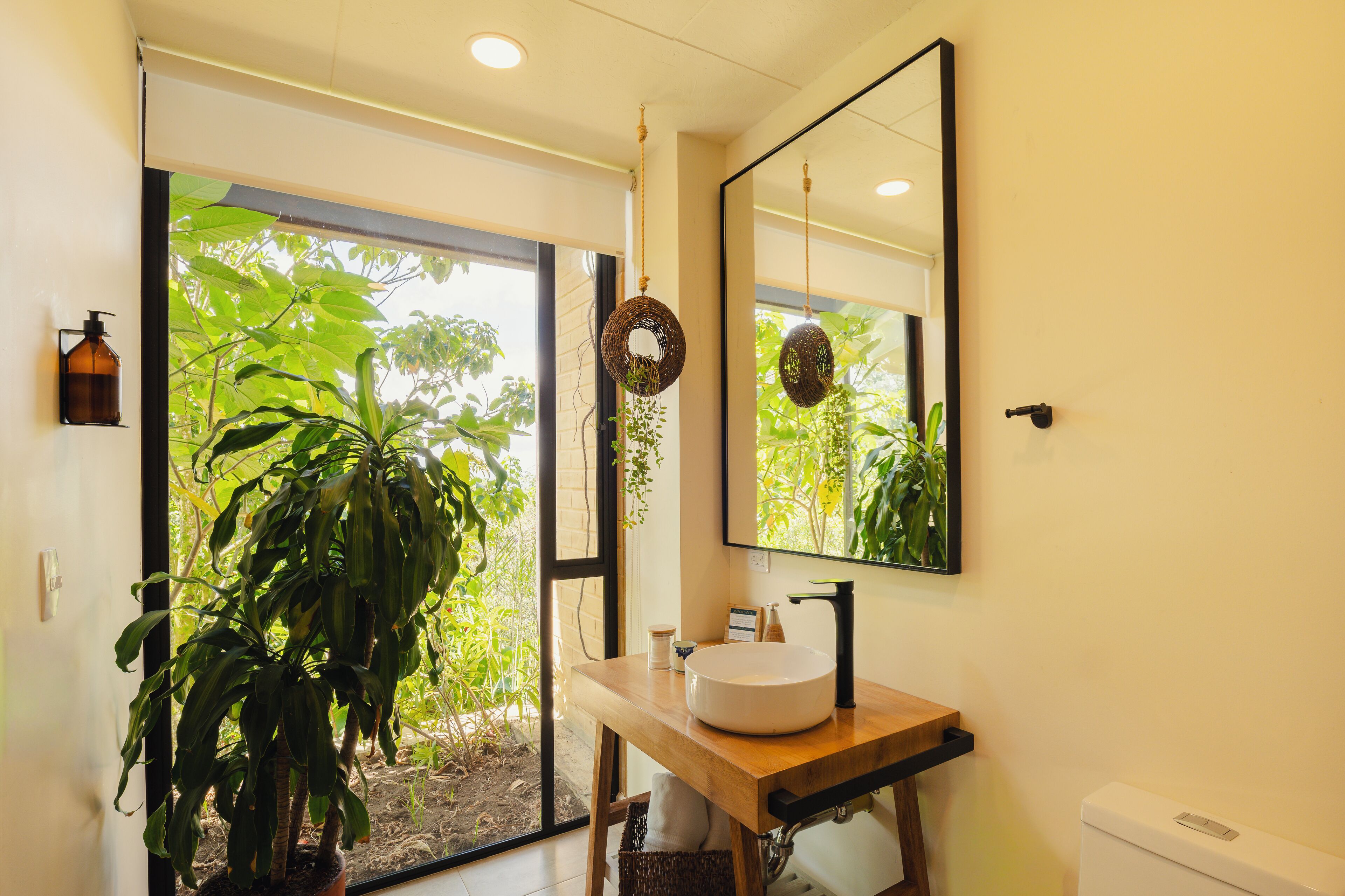 A bathroom with a large window, a wooden vanity, a white sink, and a toilet.