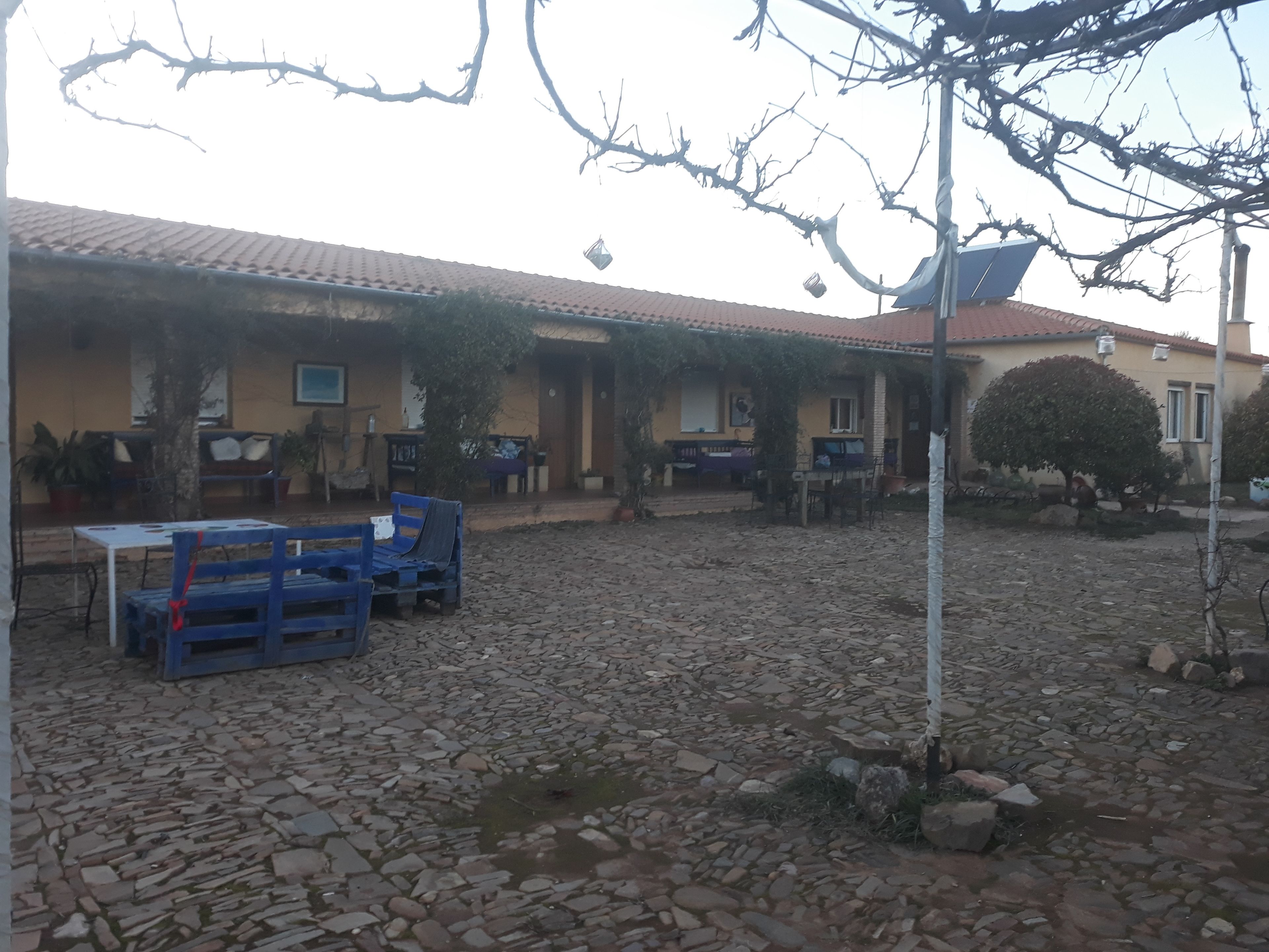 Un patio con suelo de piedra, mobiliario exterior y un edificio con tejado de baldosas.