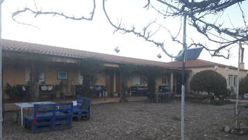 Un patio con suelo de piedra, mobiliario exterior y un edificio con tejado de baldosas.