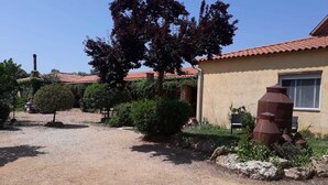 A rustic building with a gravel driveway, a chimney, and a large tree in the foreground.