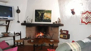 A living room with a fireplace, a television, and a painting on the wall.