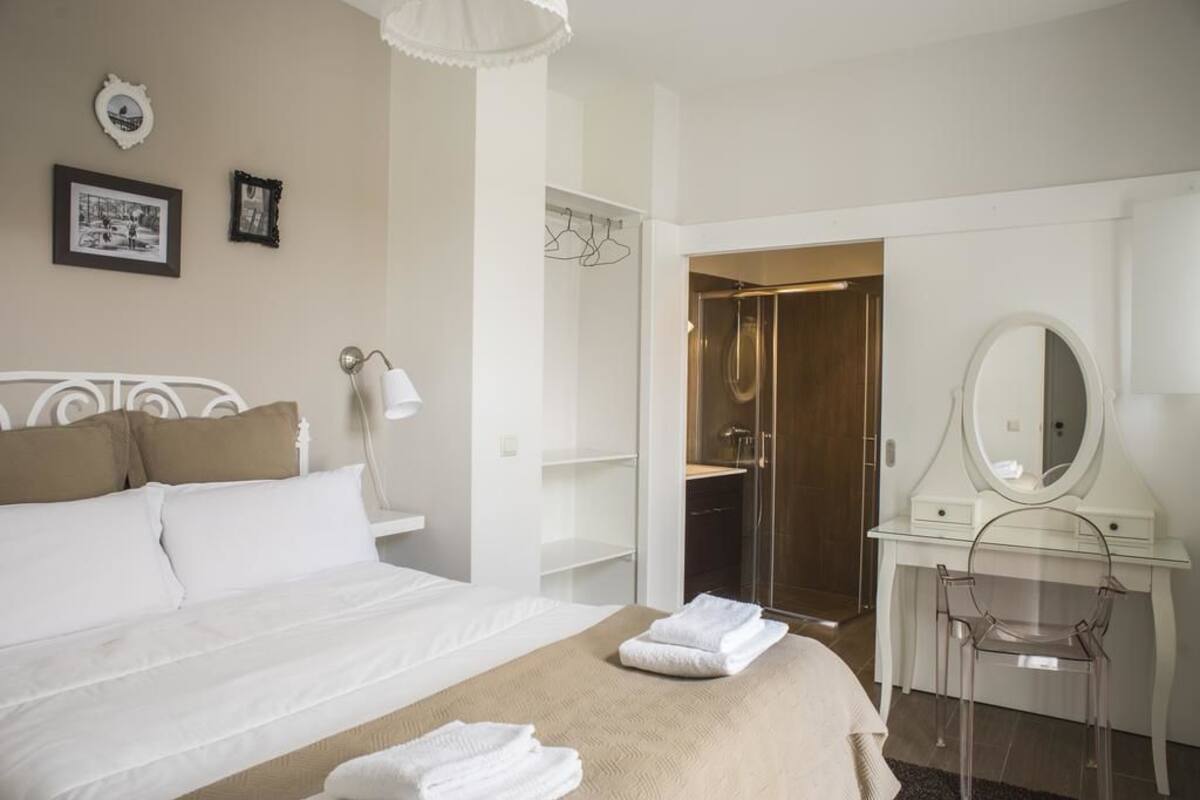 Ein Hotelzimmer mit Bett, Schminktisch mit Spiegel und Duschbereich.