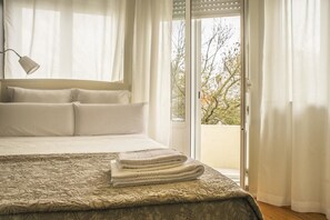 Une chambre à coucher avec un lit, une lampe et une vue sur l’extérieur, accessible par une porte coulissante.