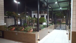 An outdoor area with a glass entrance, potted plants, and a tiled floor. - Apartamento em frente a Praia Santos (Santos)