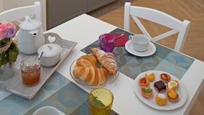 A dining area with a table set for breakfast, including croissants, pastries, and a coffee pot. - Flavourful Flat down Pratello Area - Flat in Bo (Bologna)
