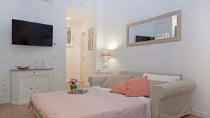 A bedroom with a bed, bedside table, lamp, TV, and a mirror. - Flavourful Flat down Pratello Area - Flat in Bo (Bologna)