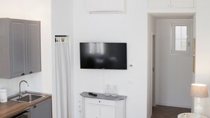 A modern kitchen with grey cabinets, a built-in oven, and a flat-screen TV mounted above the counter. - Flavourful Flat down Pratello Area - Flat in Bo (Bologna)