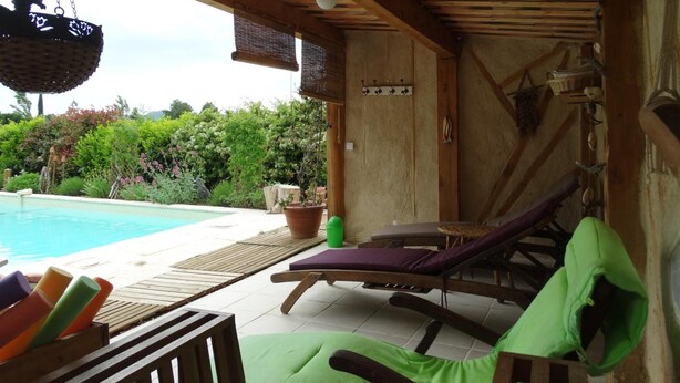 A covered outdoor area with a pool, lounge chairs, and a hanging basket. - Chambres d'hôtes Lou Cliou (Cliousclat)