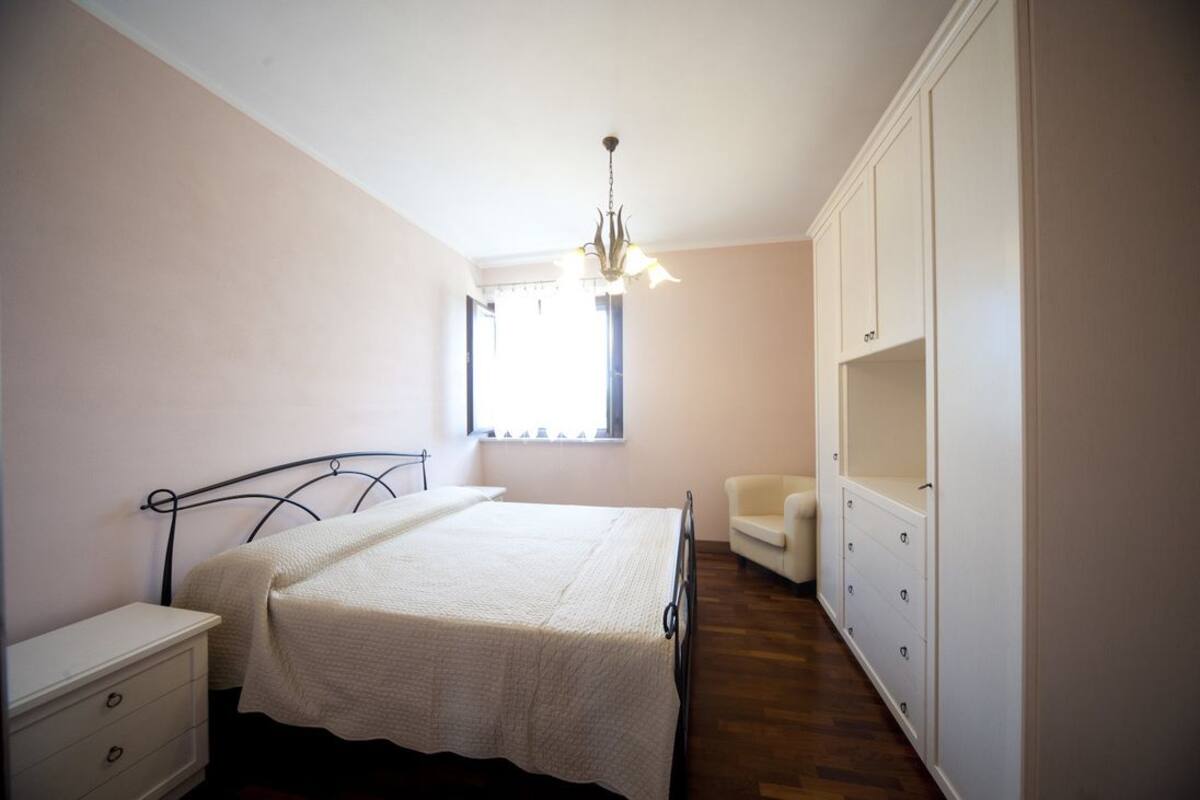 A bedroom with a bed, a nightstand, a chair, and a wardrobe.