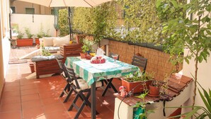 An outdoor patio with a table and chairs, surrounded by potted plants and a large umbrella. - Secret Garden Via San Rocco - Flat in Bo (Bologna)