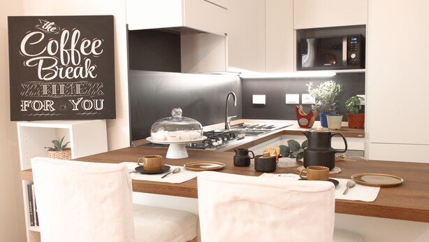 A modern kitchen with a dining area, featuring a coffee-themed sign, a stove, microwave, and various kitchen appliances. - Secret Garden Via San Rocco - Flat in Bo (Bologna)