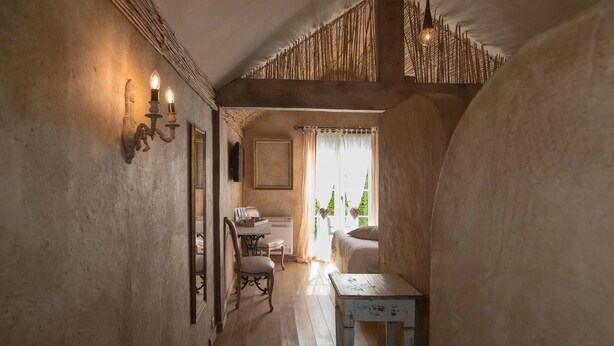 Un couloir étroit avec un plafond rustique, une table en bois et une chaise.