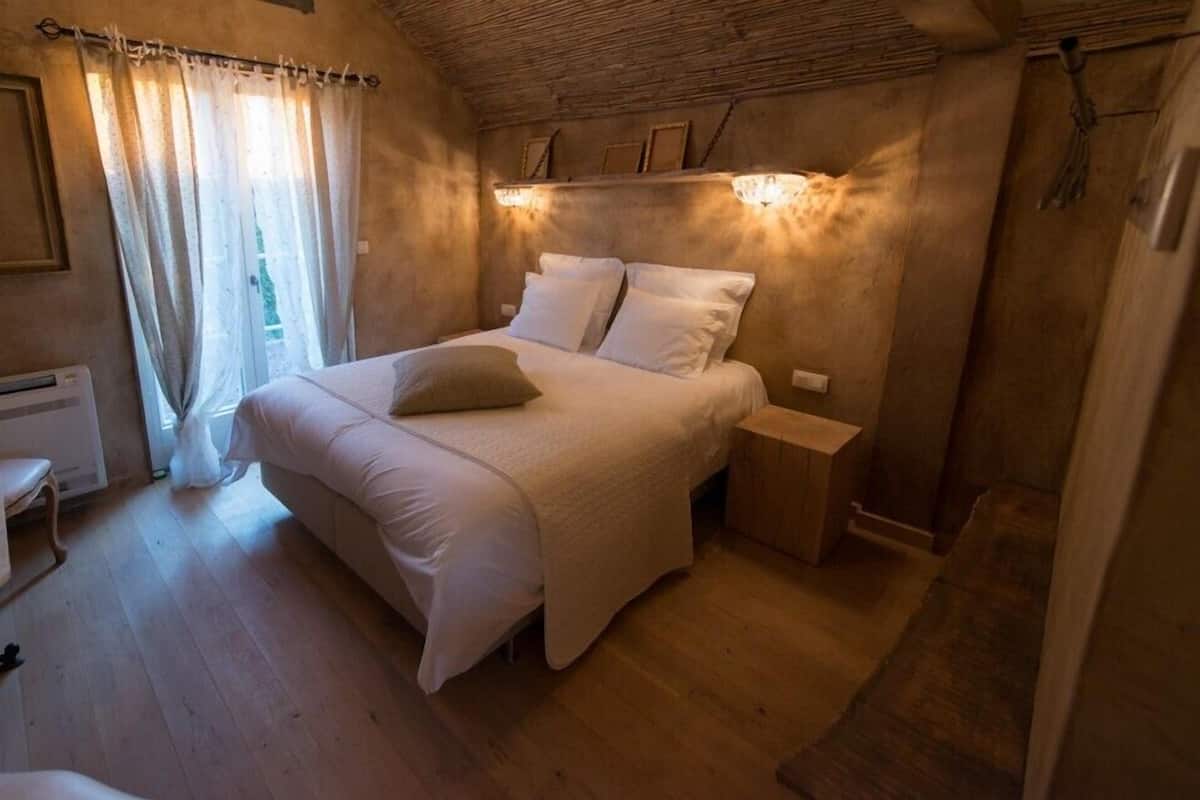 Un dormitorio acogedor con una cama grande, una mesita de noche y una ventana con cortinas.