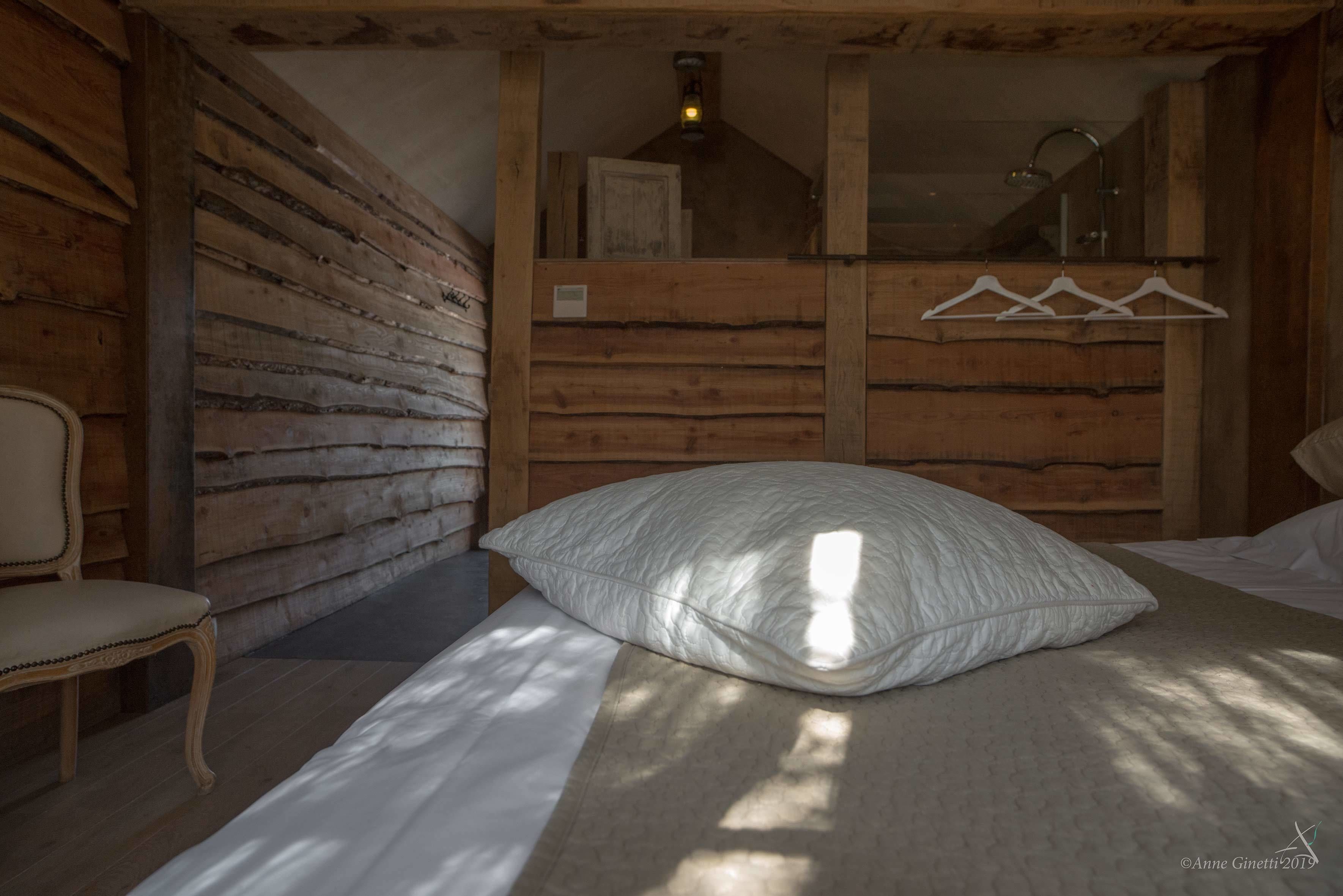 Een gezellige kamer met een bed, een stoel, houten wanden en een kledingrek.
