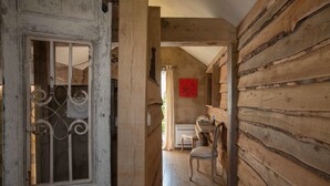 Un intérieur rustique en bois, avec un coin repas, une chaise et une œuvre d’art rouge accrochée au mur.
