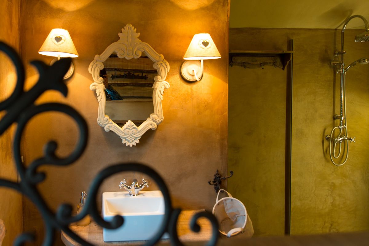 Un baño con un lavamanos blanco, dos lámparas de pared, un espejo y una ducha.
