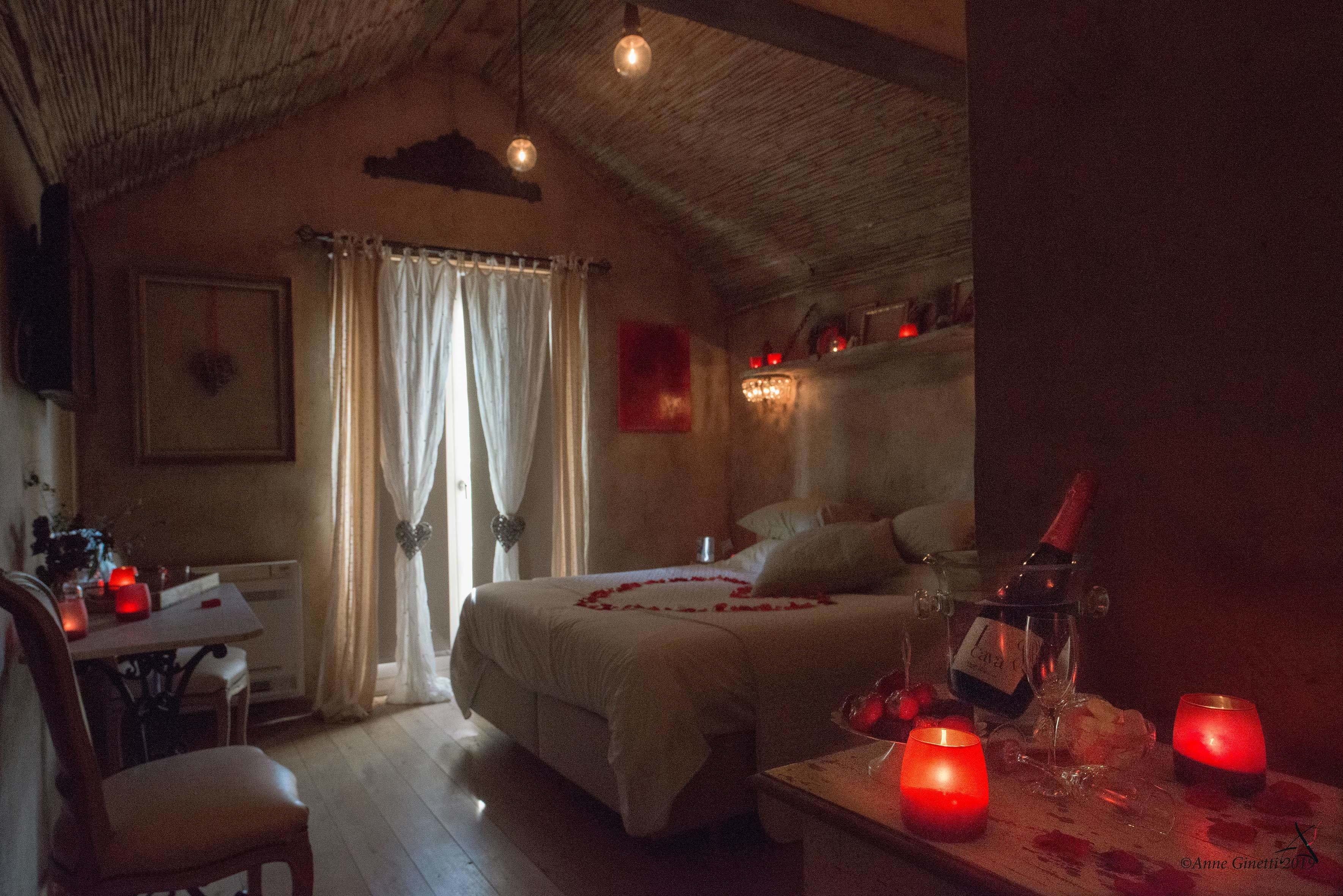 A cozy bedroom with a bed, bedside table, and a bottle of wine.