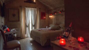 A cozy bedroom with a bed, bedside table, and a bottle of wine.