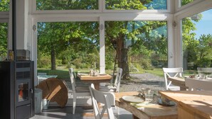 Un espace repas extérieur moderne, avec des meubles blancs et un poêle à bois.