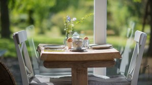 Une table à manger avec des chaises, un vase de fleurs, des assiettes et des tasses.