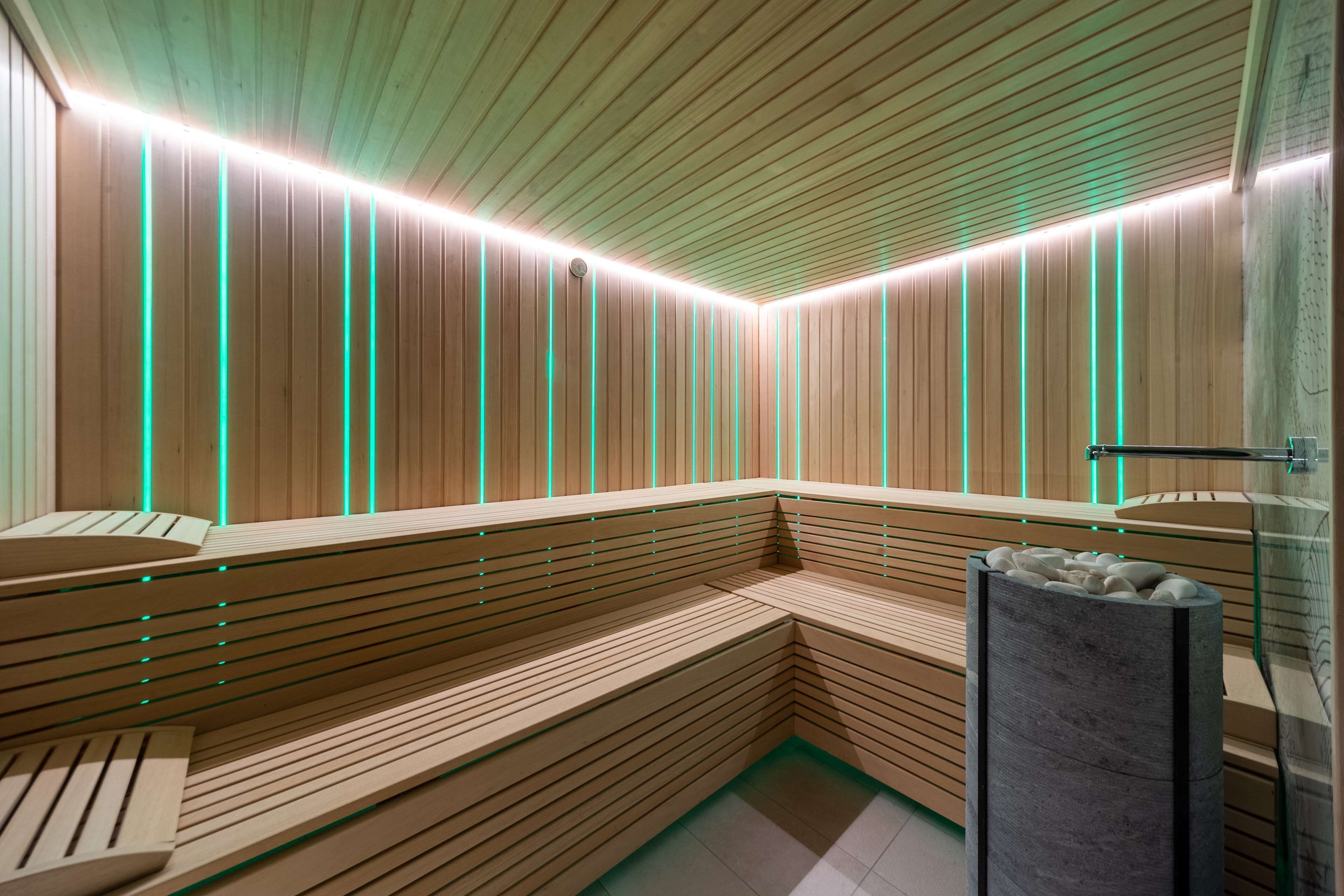 A modern sauna with wooden benches and a glass wall.