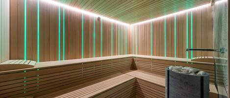 A modern sauna with wooden benches and a glass wall.