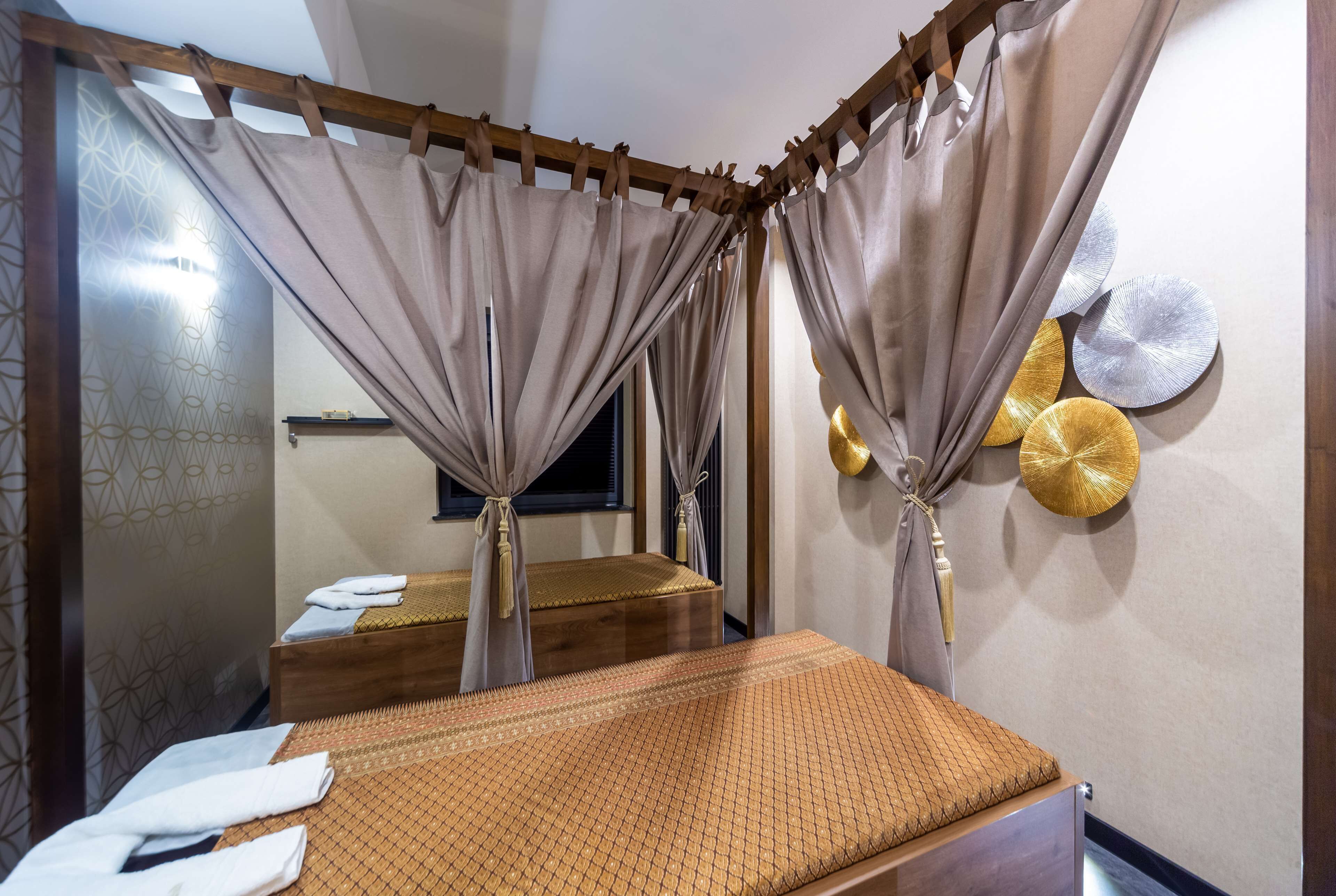 Een kamer met een bed, gordijnen en een muur met decoratieve borden.
