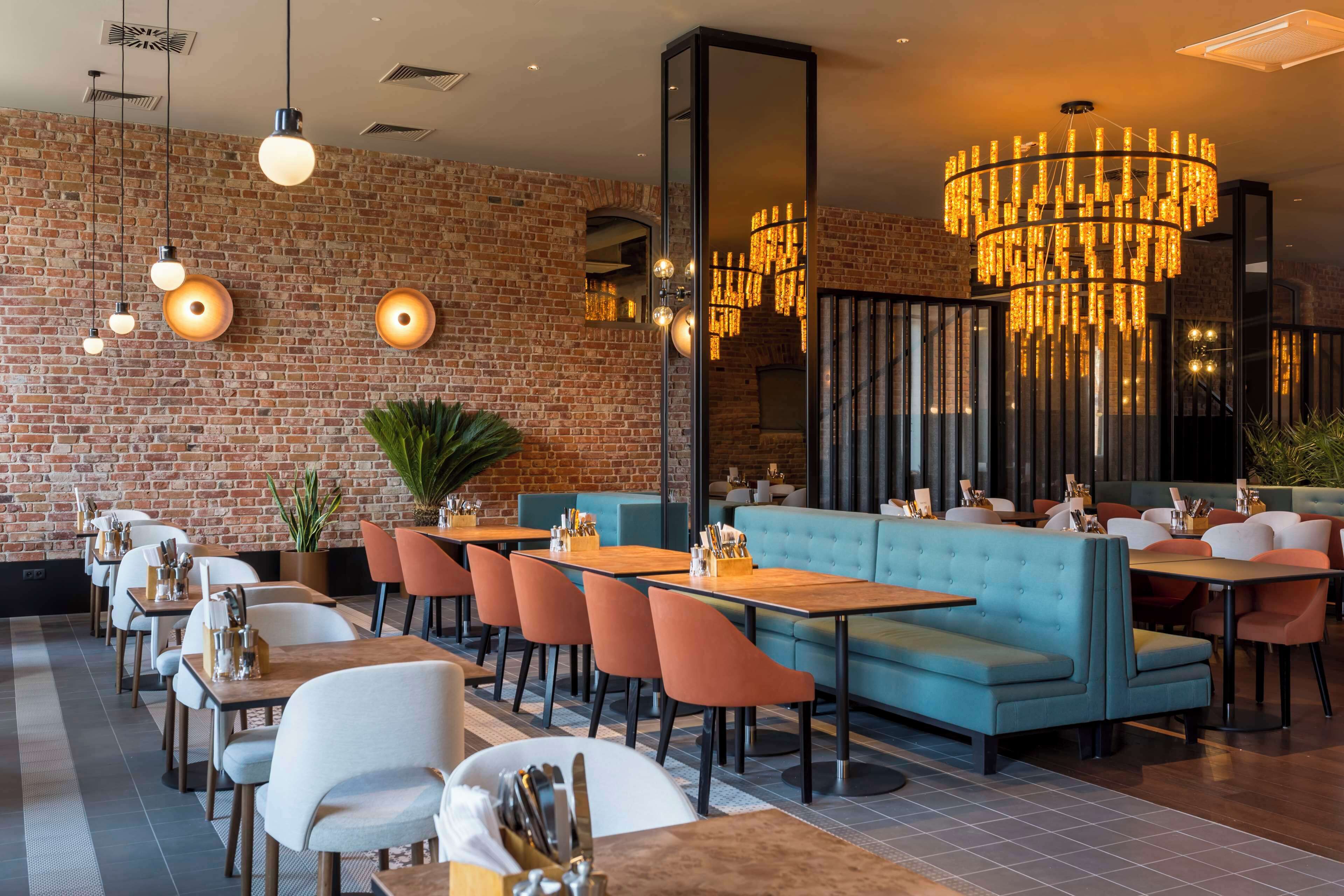 A restaurant with brick walls, wooden tables, and blue seating.
